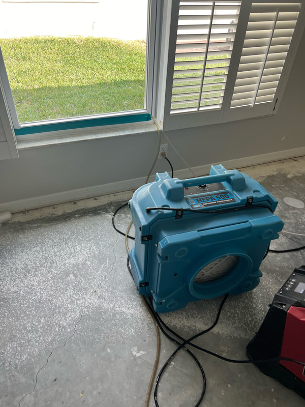 Air scrubber and dehumidifier set up on a bare concrete floor